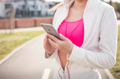 Aplikacionet më të mira falas për trupin bikini : Grua në xhaketë të bardhë që mban iPhone argjend